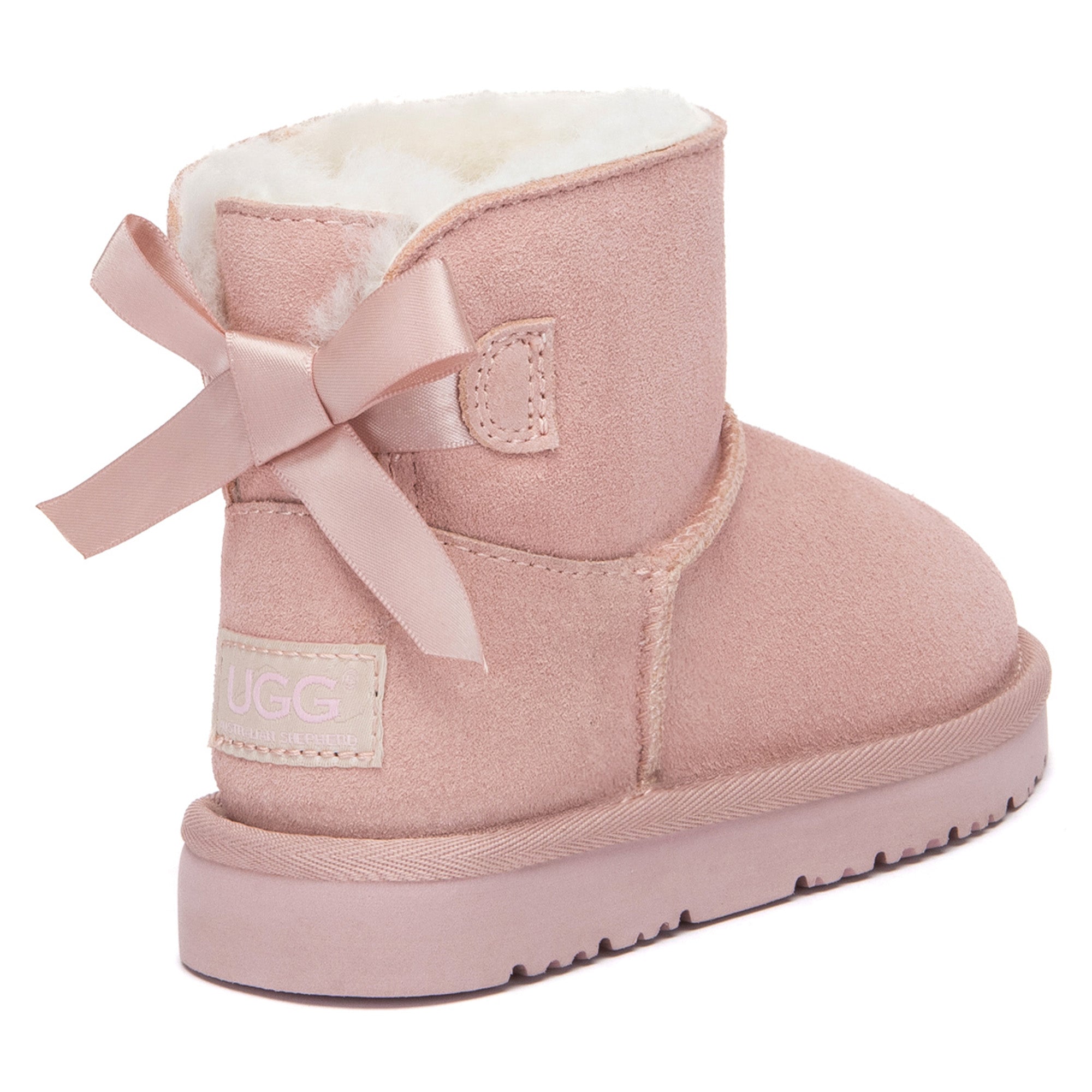 Kids mini classic UGG boots with back bow detail in tan, featuring plush sheepskin lining and durable rubber soles.